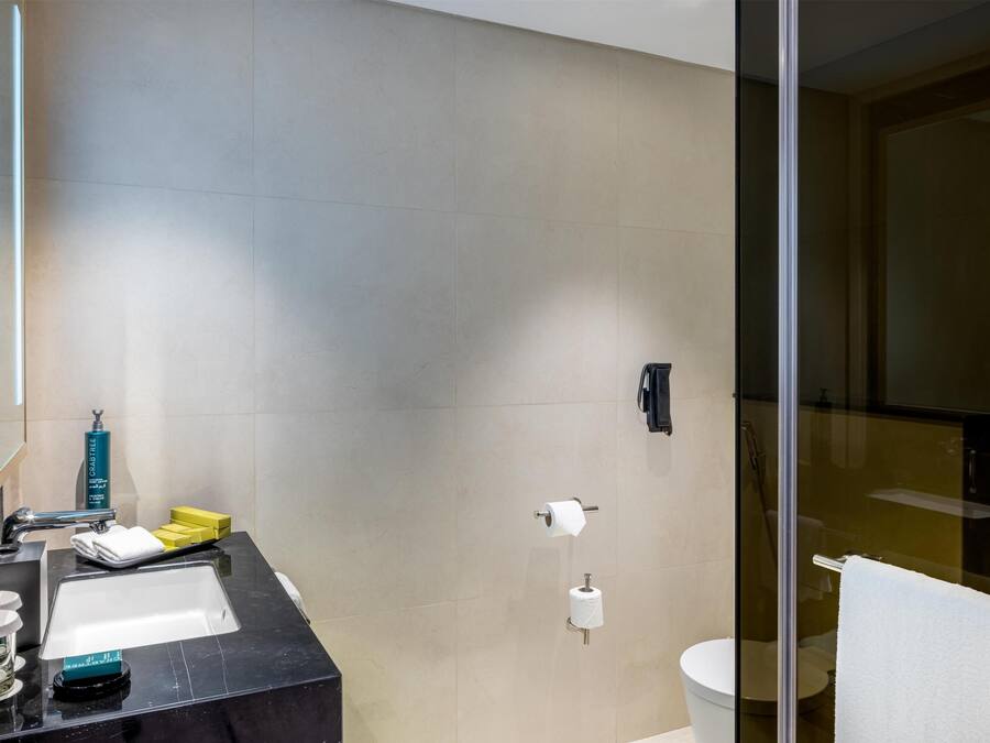 Un baño moderno con encimera negra, cabina de ducha de vidrio y un inodoro.