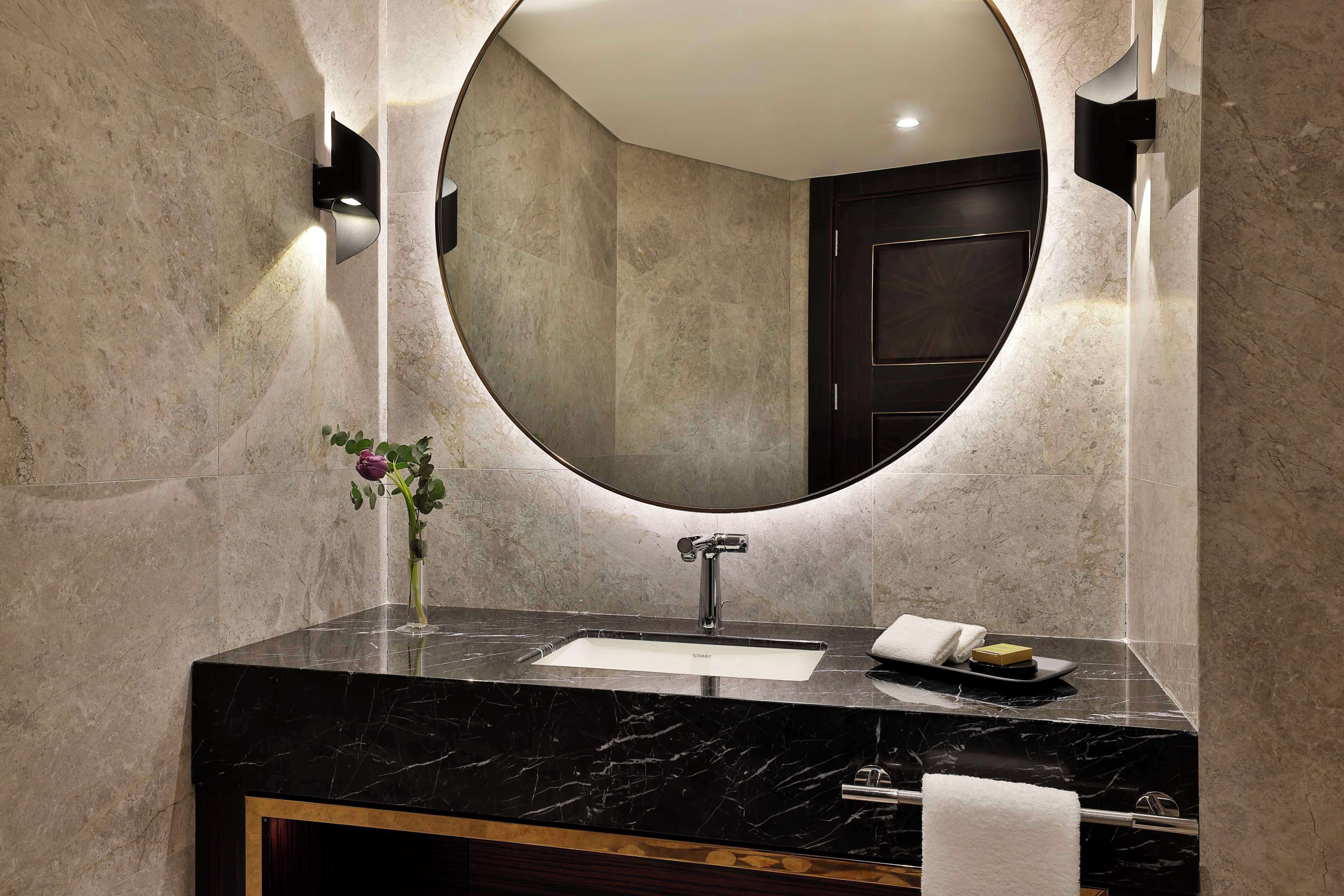 A modern bathroom with a marble sink, a large mirror, and a wooden vanity.