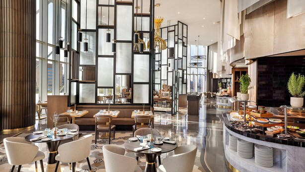 A modern hotel lobby with a central seating area, a buffet, and a large window providing natural light. - Hilton Riyadh Olaya (Riyadh)