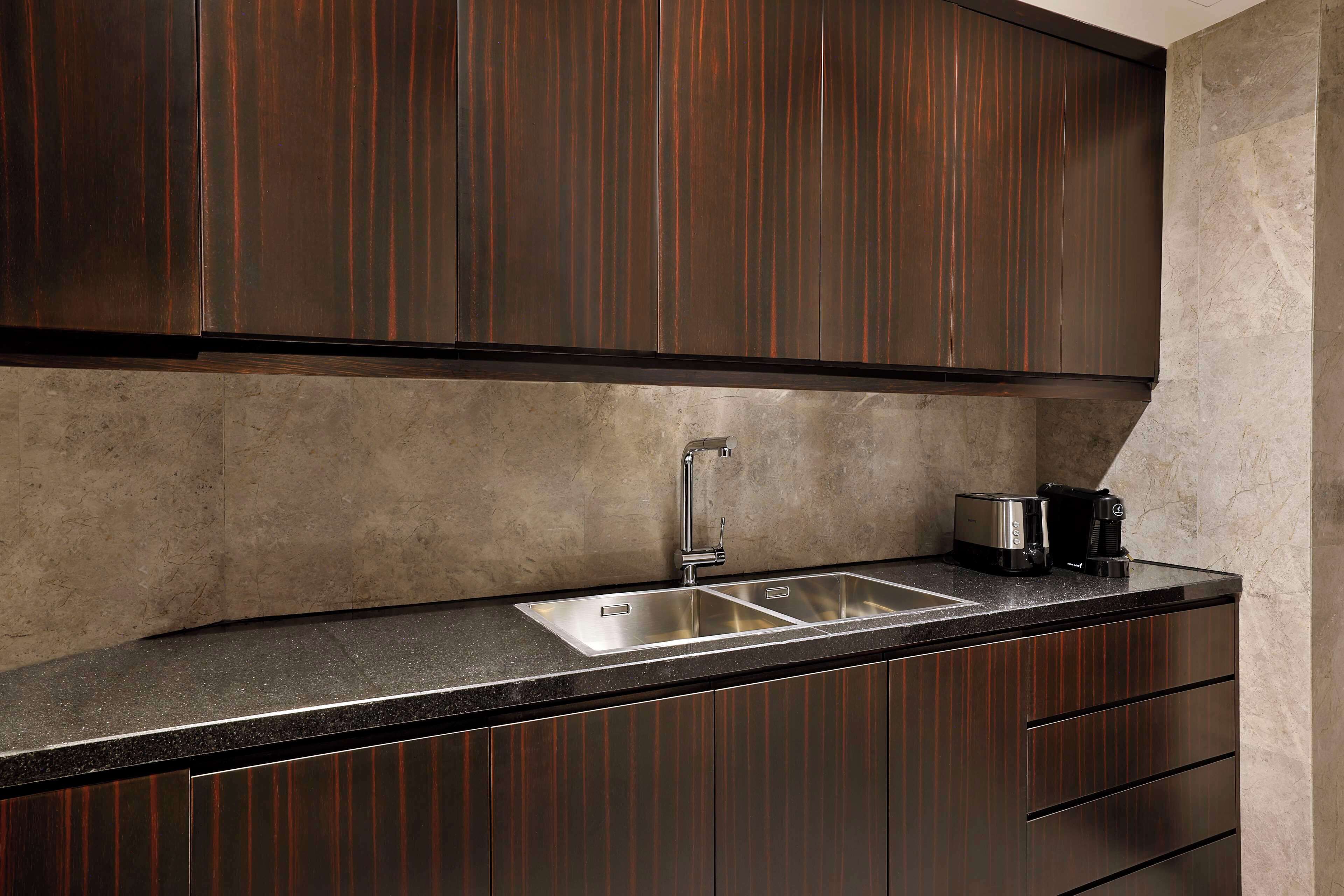 Una cocina con armarios de madera oscura, un lavamanos de acero inoxidable y una encimera.