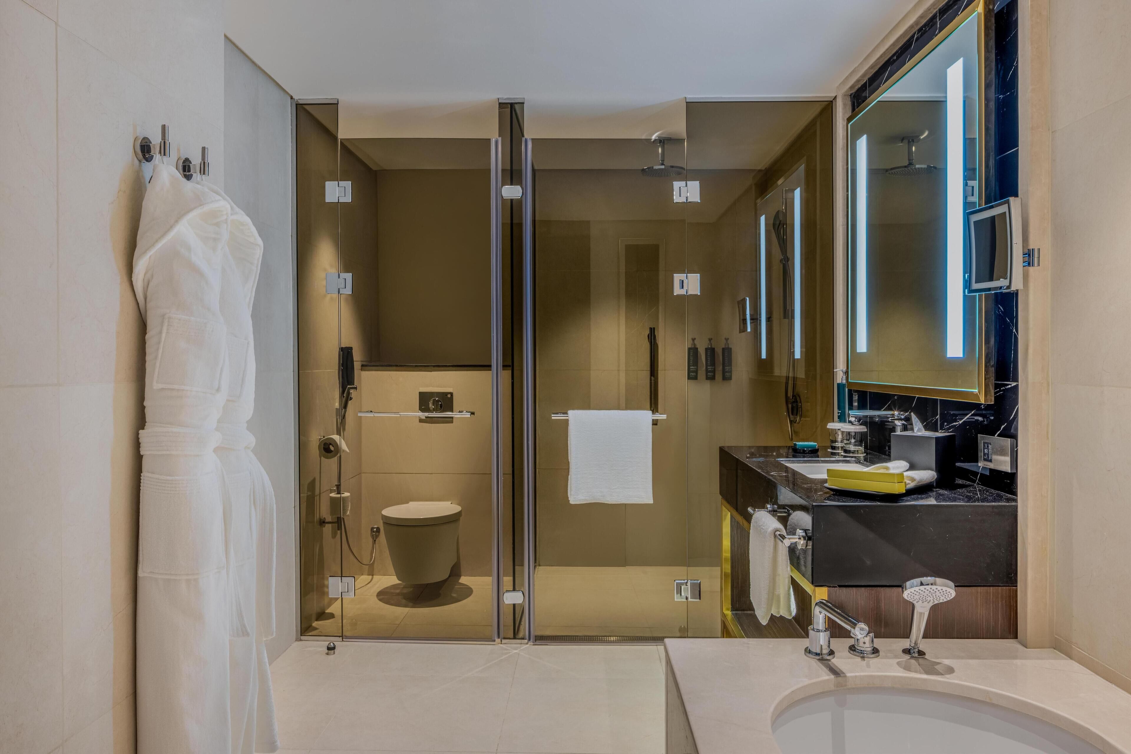 Un baño moderno con ducha de vidrio, tocador con espejo y lavamanos.