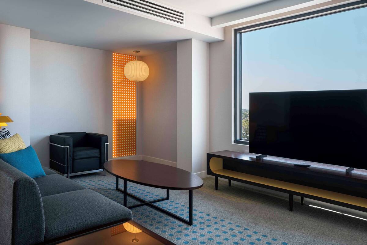 Een moderne woonkamer met een bank, een salontafel, een televisie en een groot raam.
