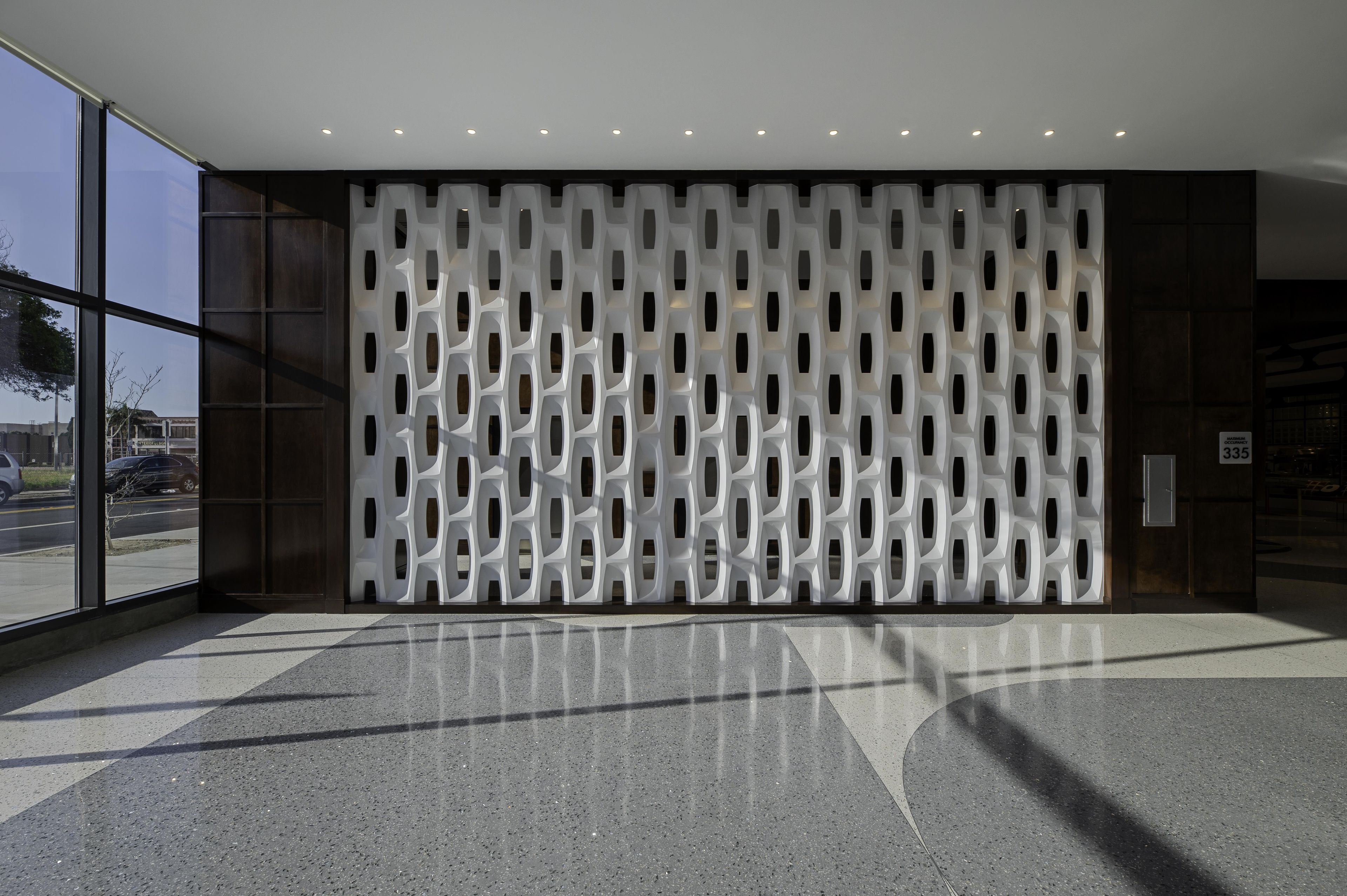 A modern interior with a patterned wall, a glass entrance, and a clean floor.