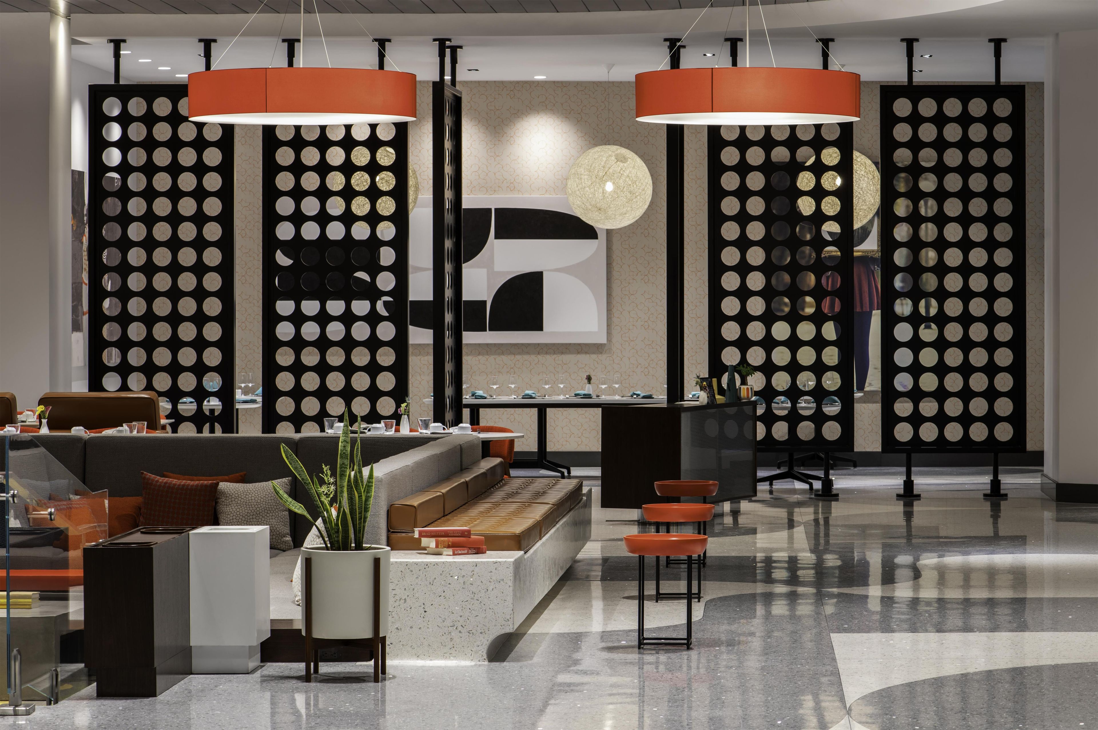 A modern hotel lobby with a seating area, a reception desk, and decorative wall panels.