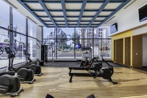 Ein Fitnessstudio mit Trainingsgeräten, großen Fenstern und Blick auf die Straße.