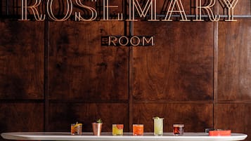 A wooden wall with the text "THE ROSEMARY ROOM" and a bar area with various drinks.