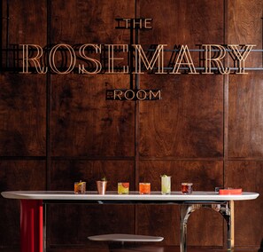 Un mur en bois sur lequel on peut lire l’inscription « THE ROSEMARY ROOM », ainsi qu’un bar proposant une variété de boissons.
