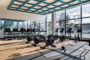 Un gimnasio con cintas de correr, bicicletas estáticas y máquinas de pesas.
