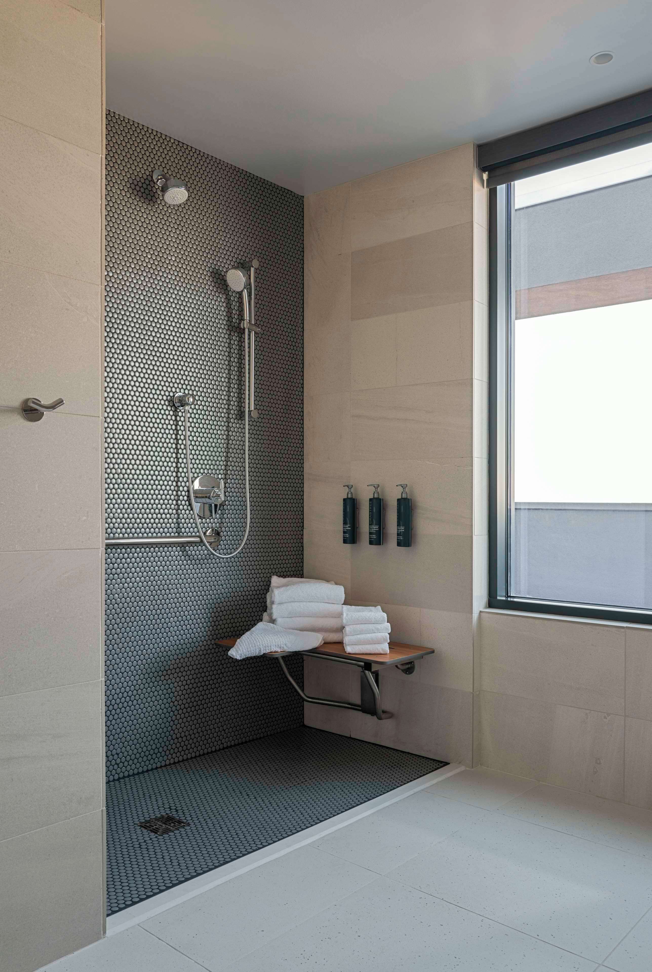 A modern bathroom with a shower, a towel rack, and a window.