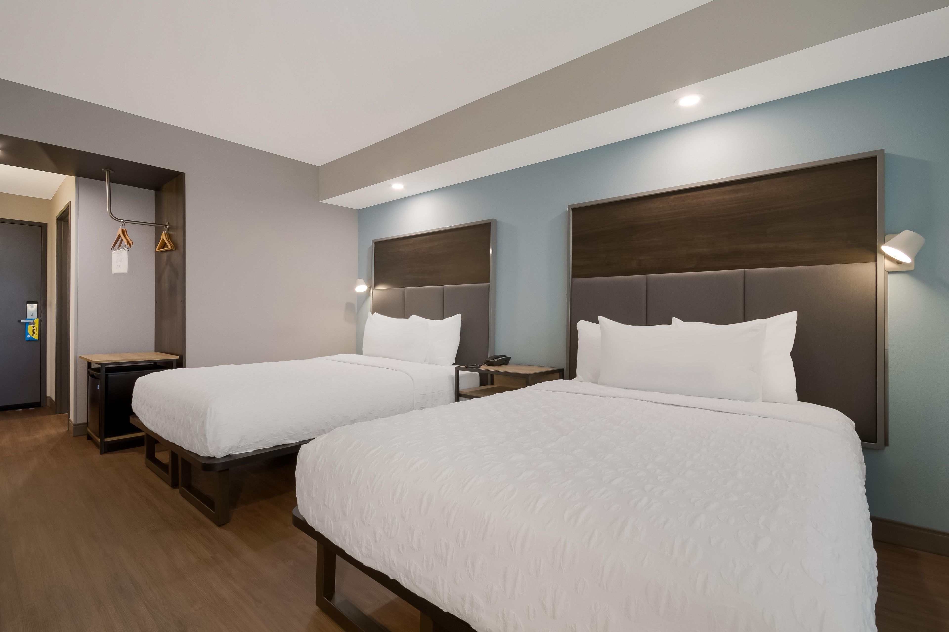 A hotel room with two beds, a desk, and a wardrobe.