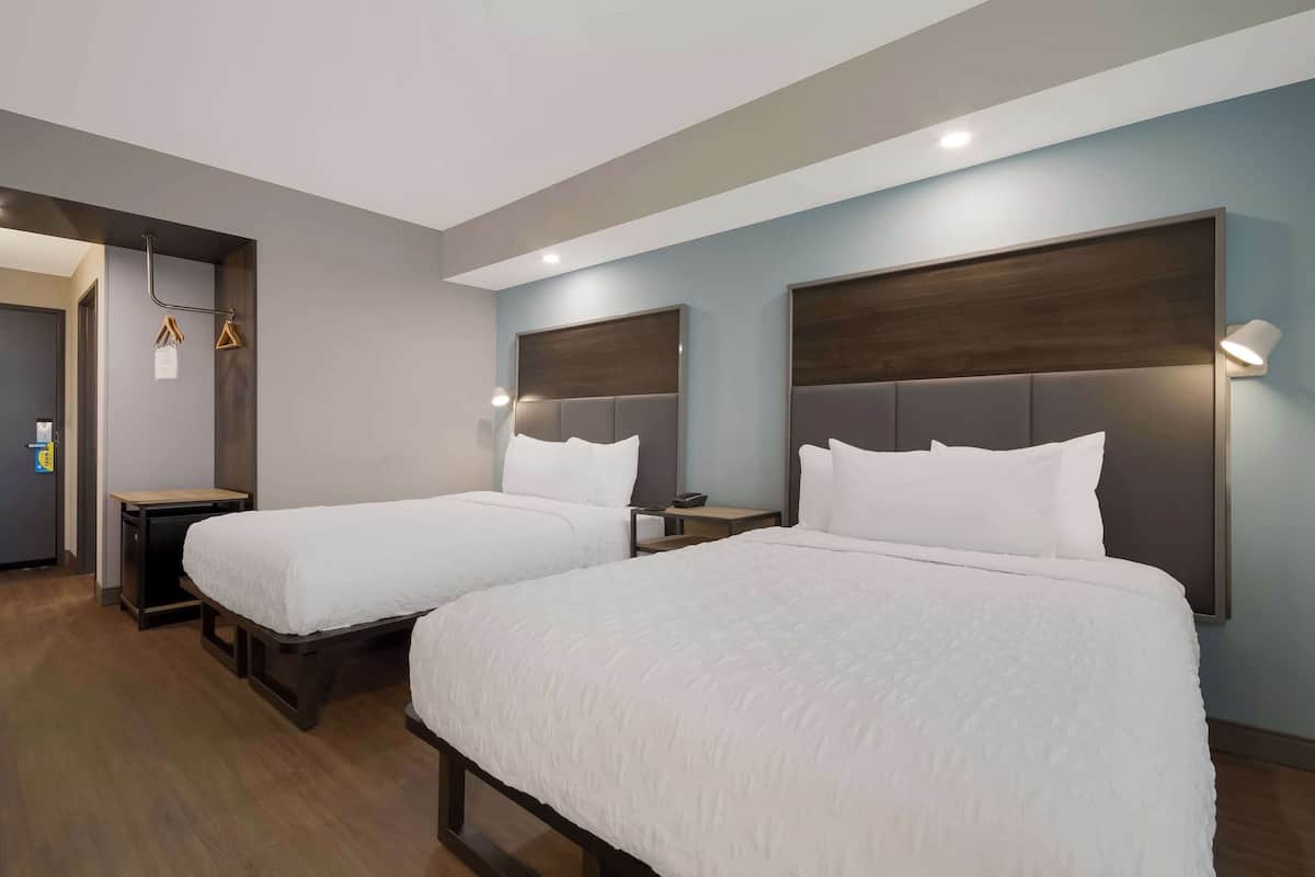 A hotel room with two beds, a desk, and a wardrobe.