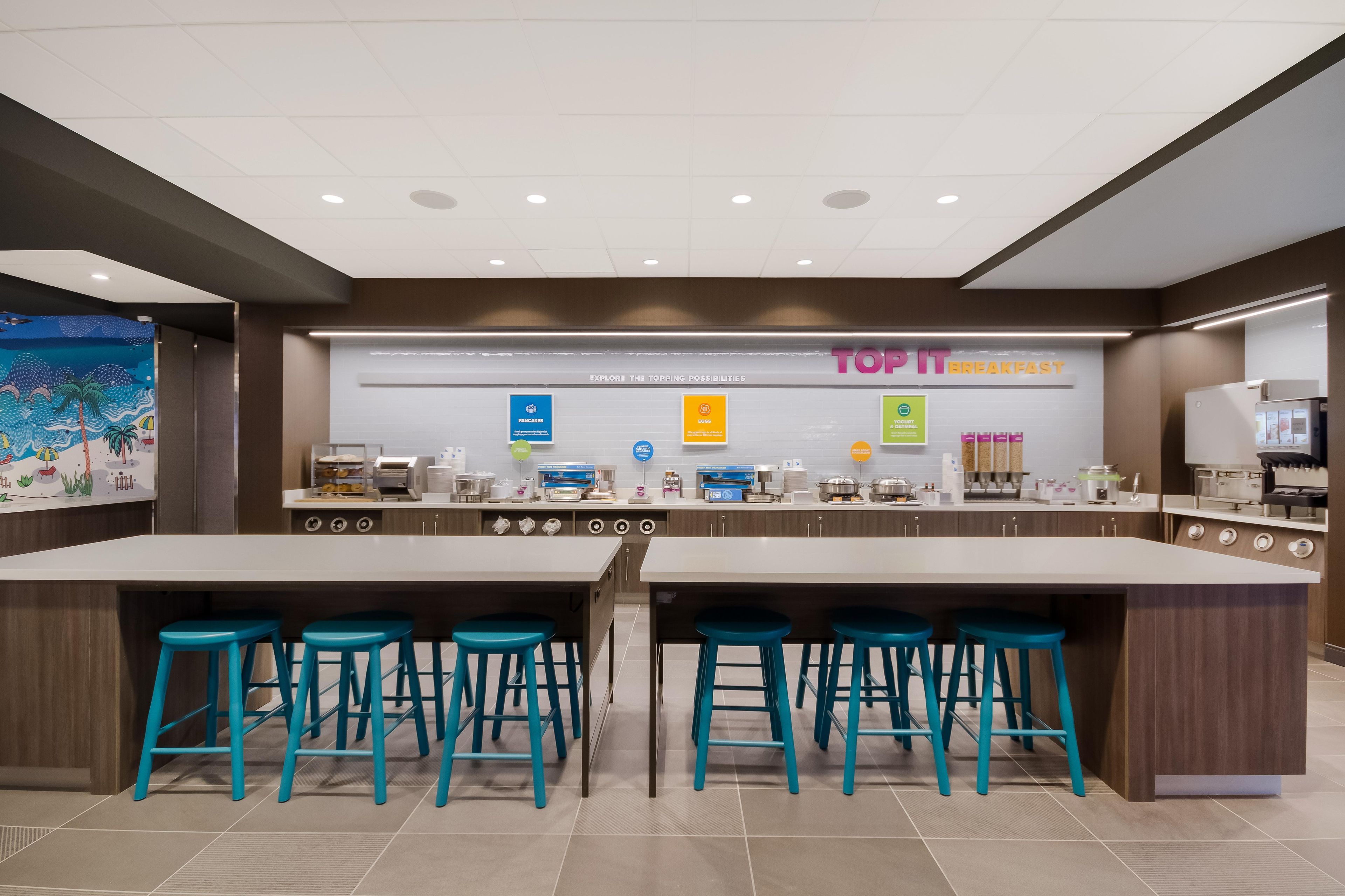 A modern breakfast area with a central island, bar stools, and a variety of breakfast options displayed.