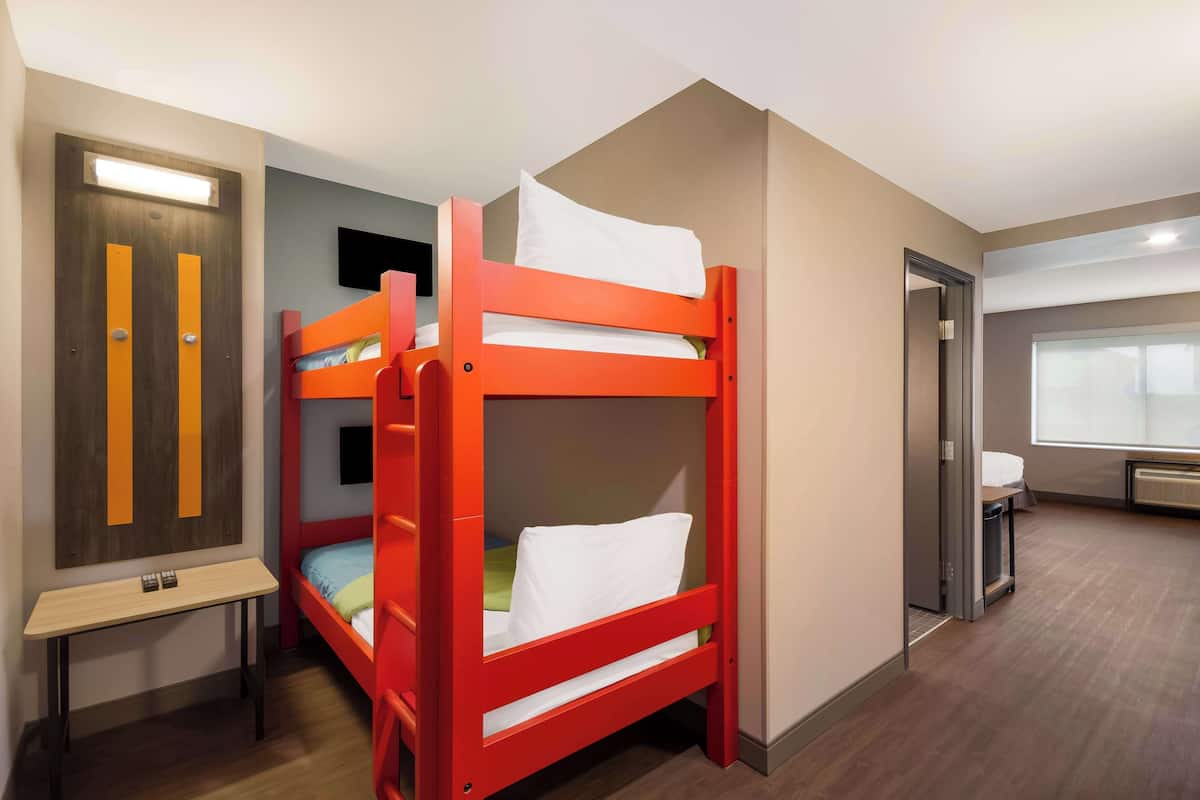 A bunk bed room with a desk and a TV.