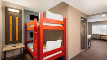 A bunk bed room with a desk and a TV.