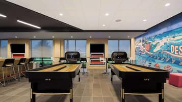 A pool hall with two pool tables, chairs, and a mural on the wall.