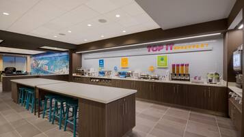 A breakfast area with a counter, stools, and various food options.