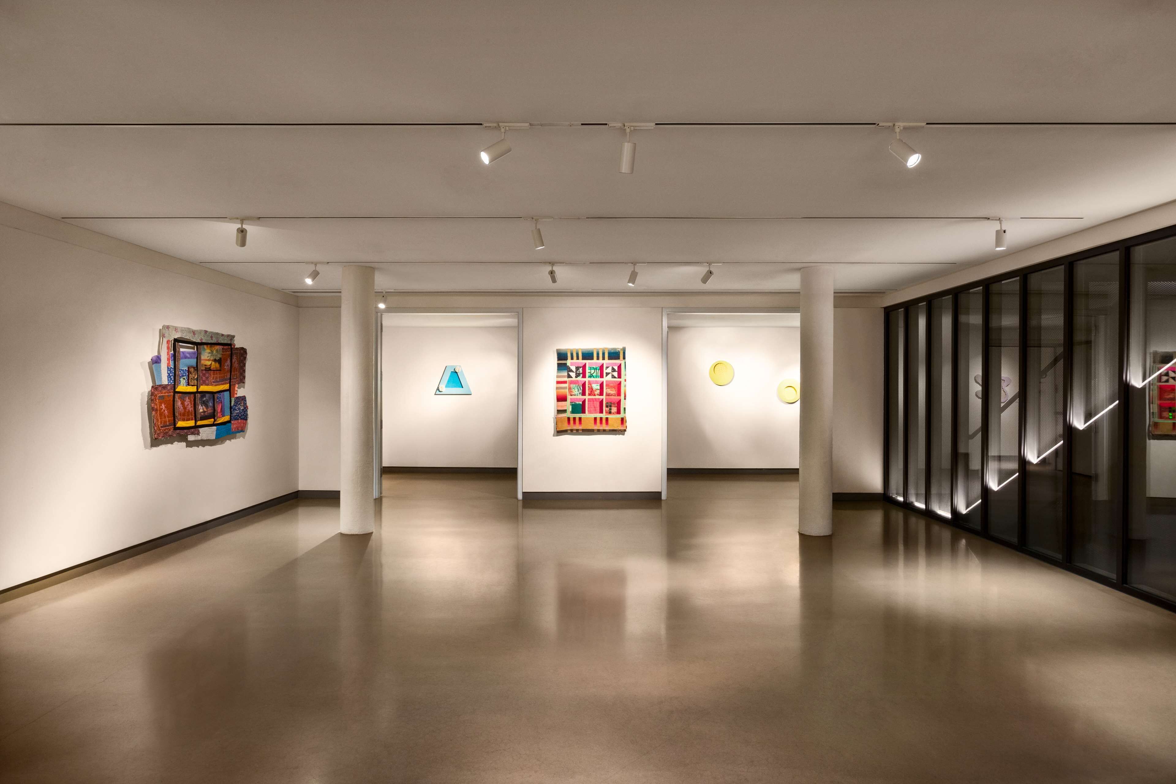An art gallery with white walls and a polished floor, featuring several artworks displayed on pedestals.
