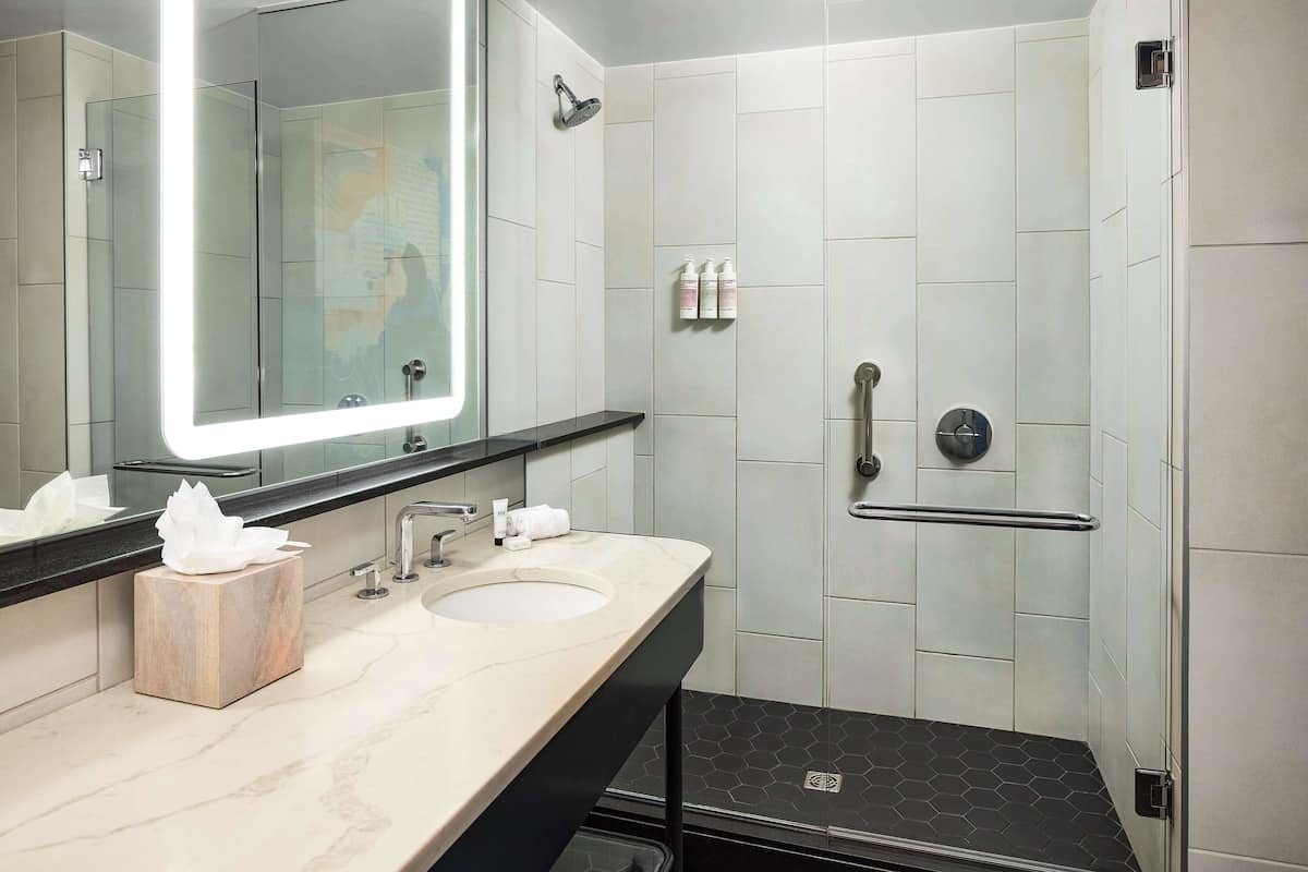 A modern bathroom with two sinks, a large mirror, and a shower area.
