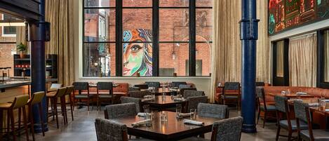 Een restaurant met een groot raam, meerdere tafels en stoelen.