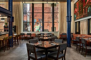 Un restaurant doté d’une grande fenêtre, de nombreuses tables et de chaises.