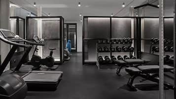 Et fitnessrum med løbebånd, håndvægte og vægtstativer.