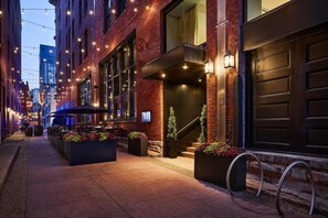 A brick building with a dark garage door, outdoor seating, and a staircase leading to the entrance. - The Untitled Nashville Hotel, Tapestry Collection by Hilton (Nashville)