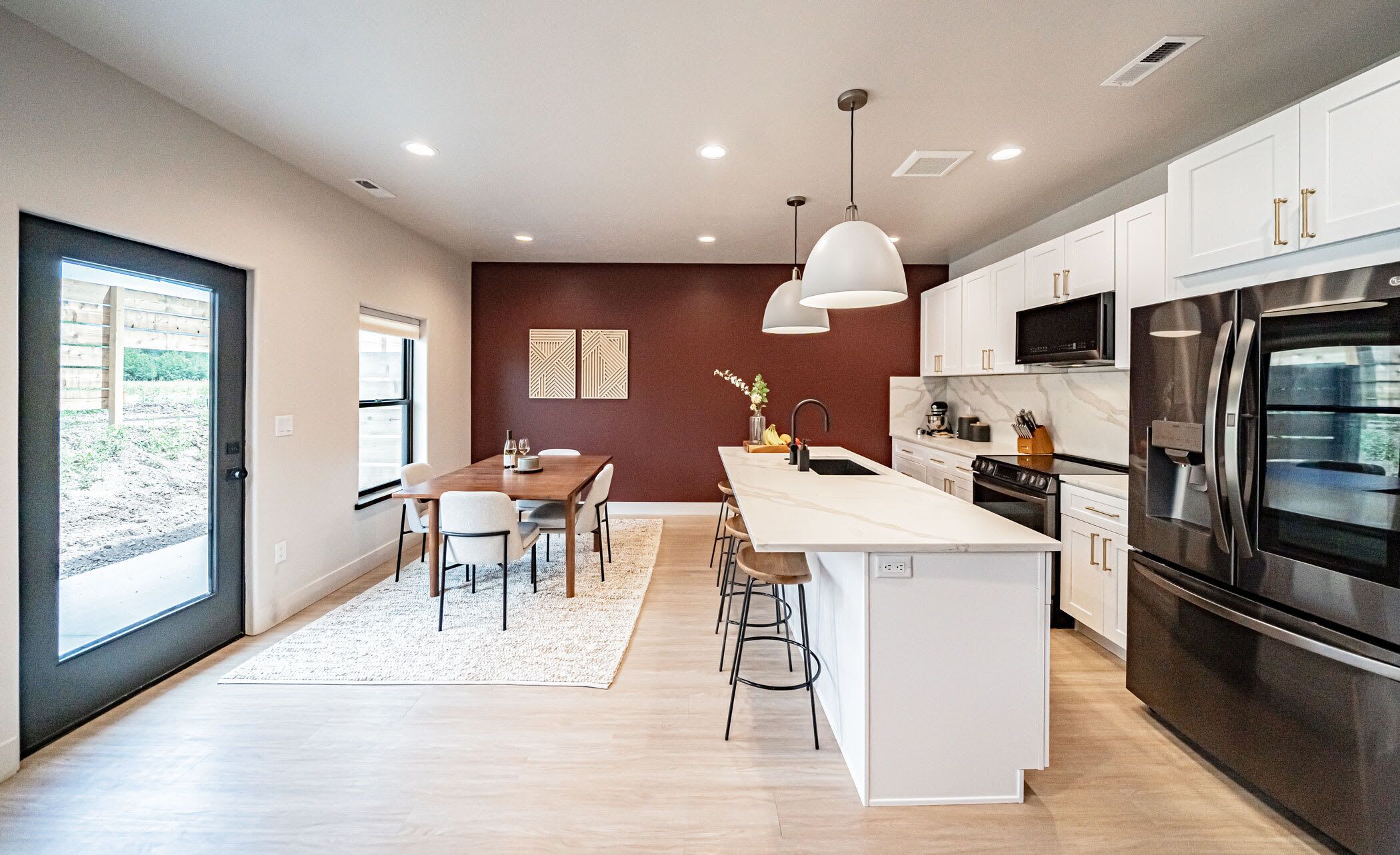 A modern kitchen with white cabinetry, stainless steel appliances, and a central island with bar stools.