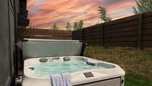 A hot tub in an outdoor setting with a wooden fence and trees in the background. - Basecamp Stays: Stylish Home - Hot Tub, AC, Garage (Driggs)
