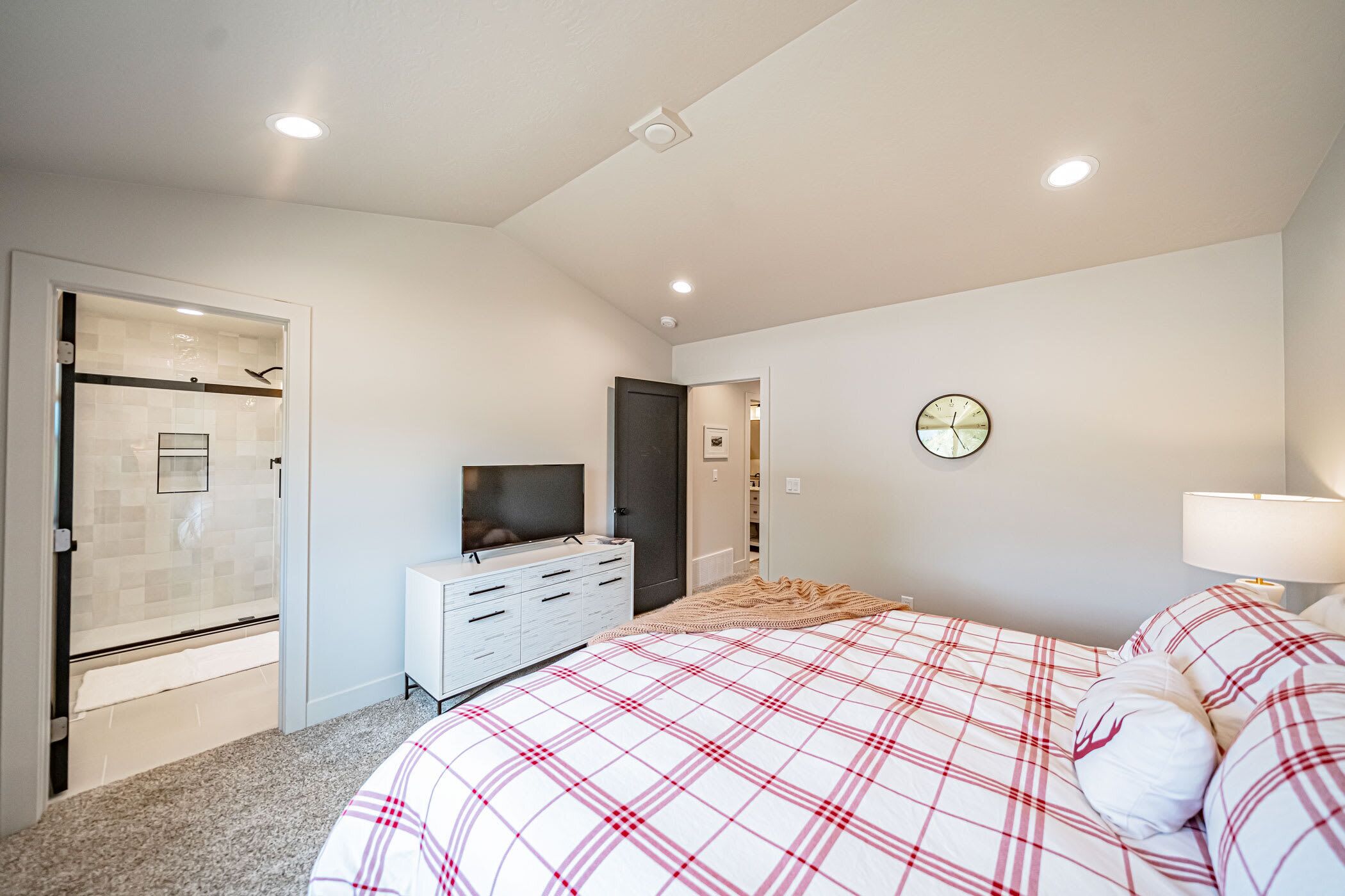 Ein Schlafzimmer mit einem großen Bett, einem Fernseher, einem begehbaren Kleiderschrank und einer Dusche.