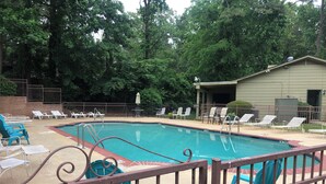 A swimming pool with lounge chairs and a fenced area.