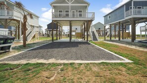 A beachfront property with a central building featuring a balcony and a covered area. - Brand New Home! Beach Views! Sleeps 6! Pets Welcome! (Bolivar Peninsula)