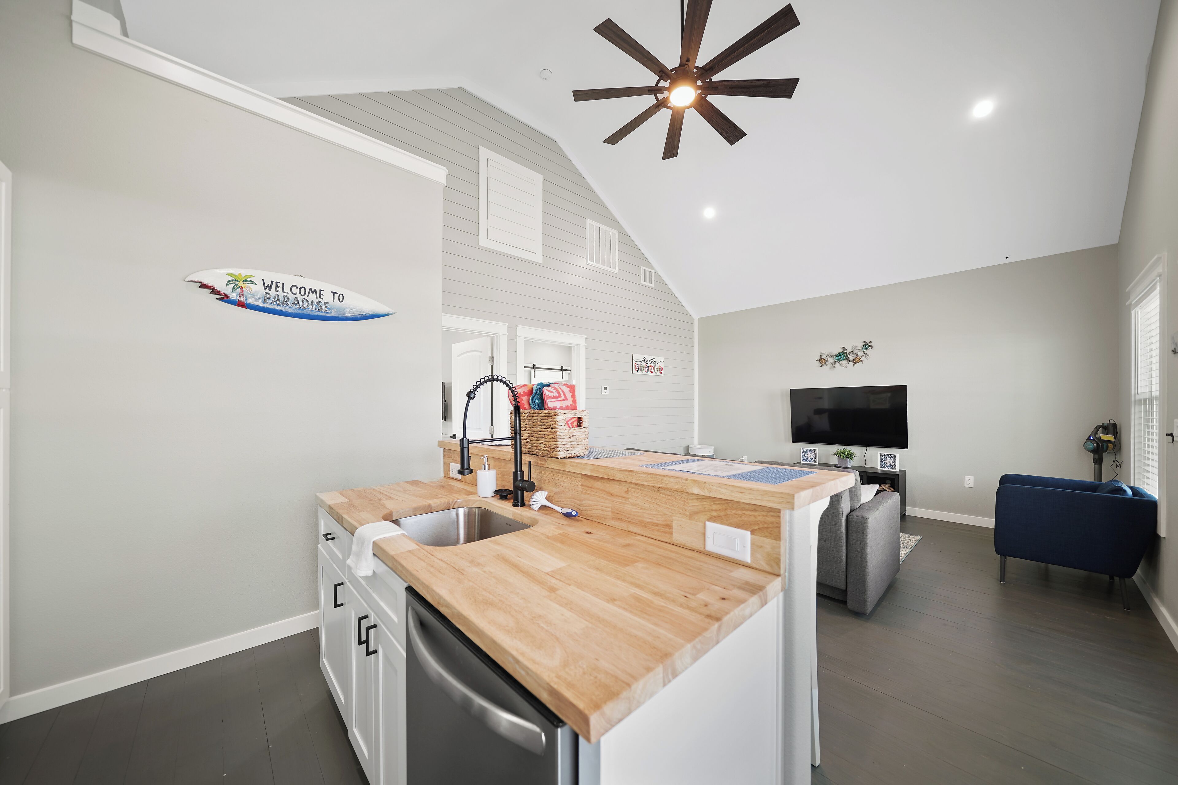 A modern kitchen with a wooden countertop, a built-in dishwasher, and a ceiling fan.
