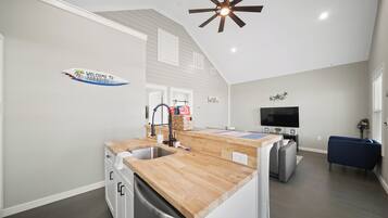 A modern kitchen with a wooden countertop, a built-in dishwasher, and a ceiling fan.