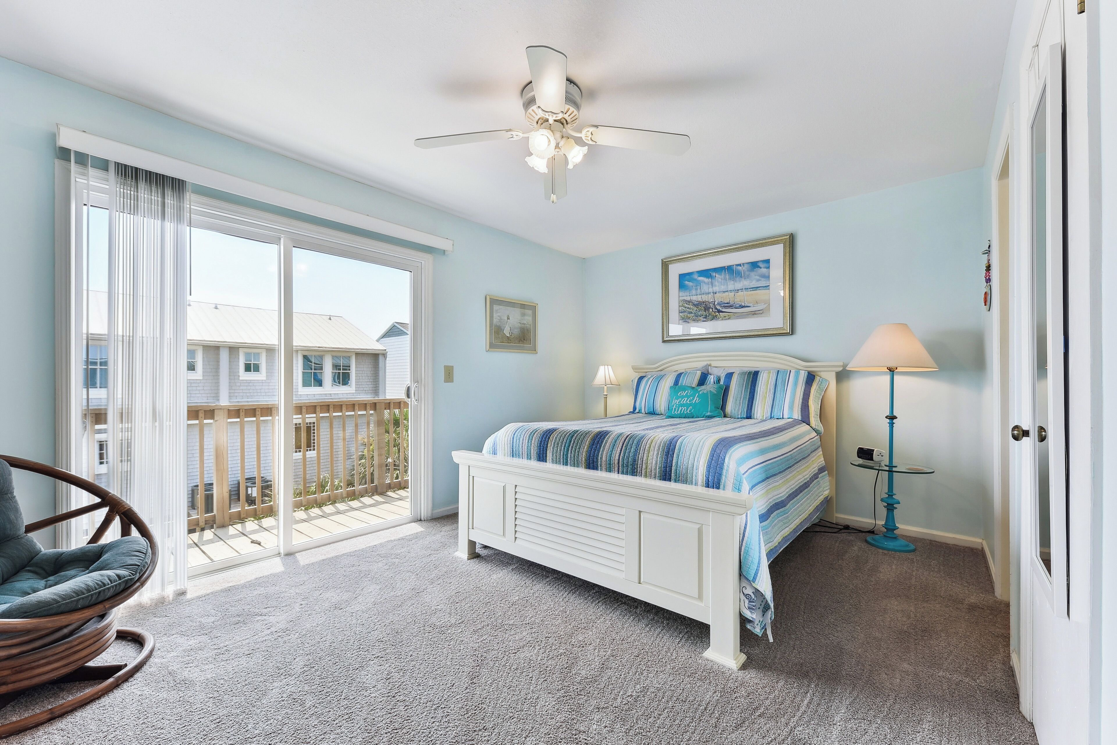 A bedroom with a bed, a ceiling fan, a window, and a balcony.