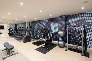 A modern gym with treadmills, elliptical machines, a bench press, and a kettlebell rack. - Hampton By Hilton London Old Street (London)