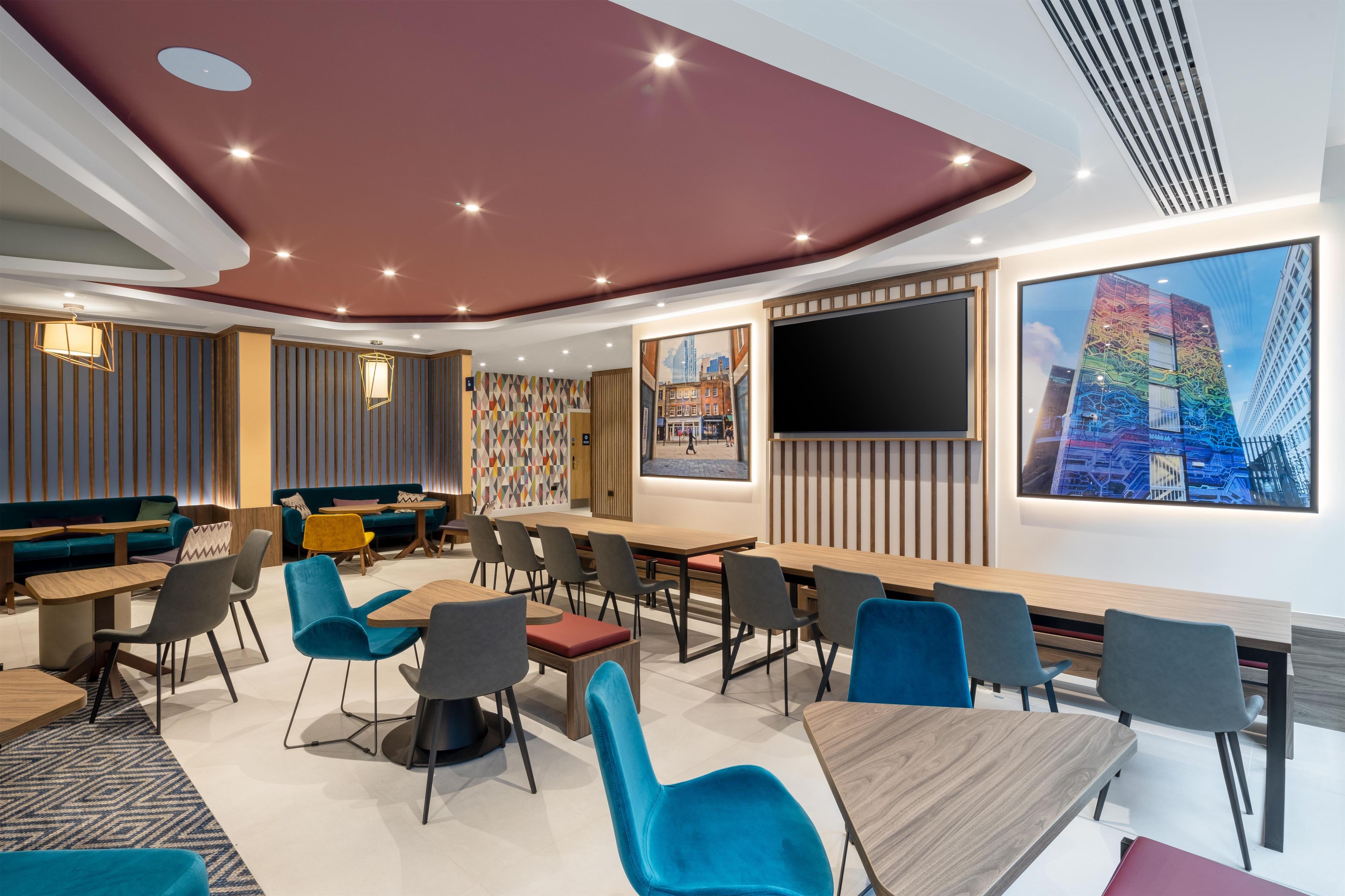 A modern conference room with tables, chairs, and a large screen.
