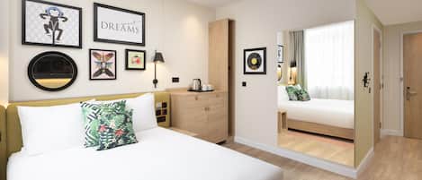 A hotel room with a bed, a nightstand, a dresser, and a door leading to another room.