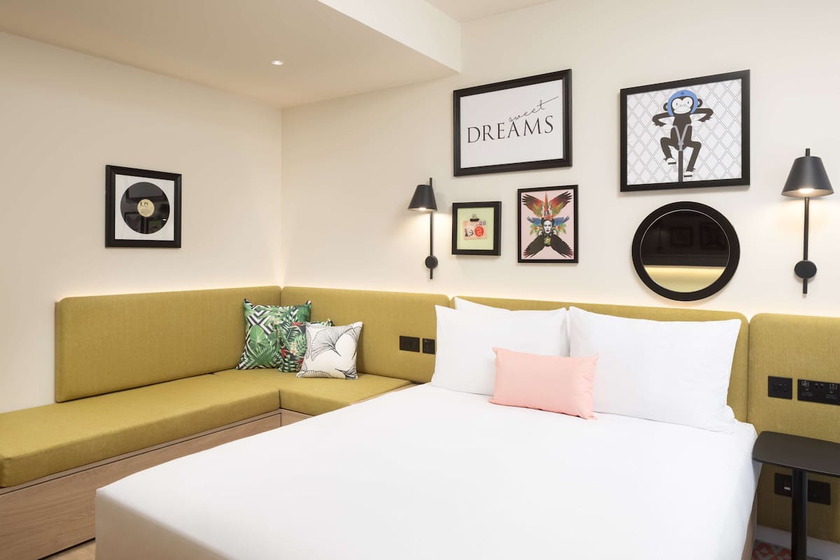 A hotel room with a bed, a sofa, and artwork on the walls.