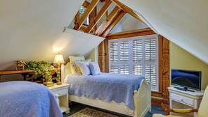 A bedroom with two beds, a television, and a window with shutters. - Romantic Cottage in Washington Historic District (Washington)