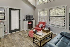 Ein Wohnzimmer mit Kamin, einem roten Sessel, einem blauen Sofa und einem Holztisch.