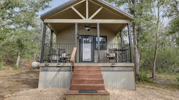 A small, single-story cabin with a porch, a door, and a staircase leading up to it.
