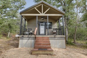 Eine kleine, eingeschossige Holzhütte mit einer Veranda, einer Tür und einer Treppe, die zu ihr hinaufführt.