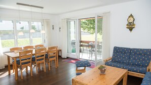 A room with a dining table, chairs, a sofa, and a clock on the wall. - Family basecamp for biking and skiing (Lenzerheide/Lai)