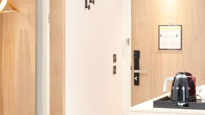 A modern kitchen with a wooden countertop, a black coffee maker, and a framed informational poster on the wall. - Hampton By Hilton Rochdale (Rochdale)