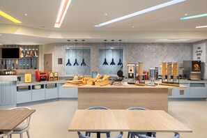 A modern kitchen with a central island, built-in appliances, and a variety of food items displayed. - Hampton By Hilton Rochdale (Rochdale)