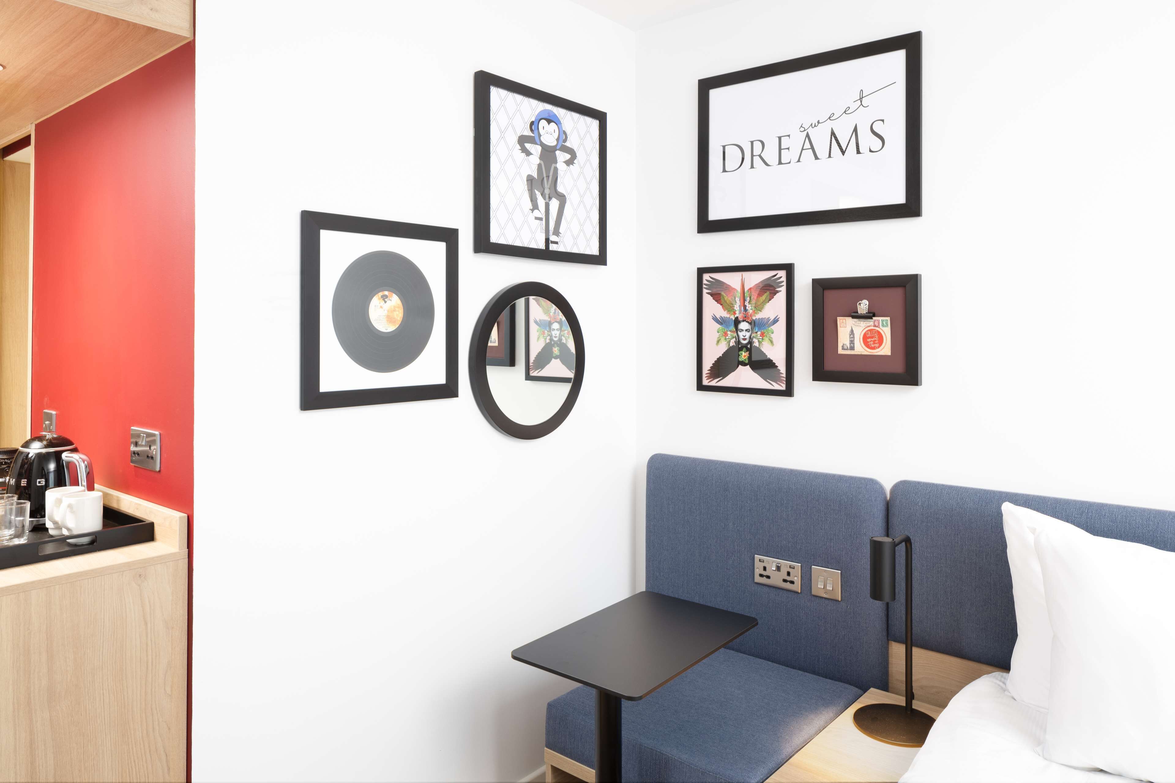 Habitació moderna amb un sofà blau, una taula petita i una paret decorada amb quadres.