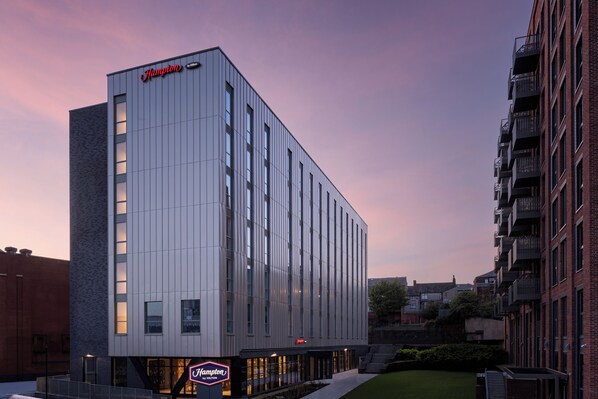 A modern hotel building with a prominent "Hampton by Hilton" sign, featuring a clean, vertical facade and a well-lit entrance. - Hampton By Hilton Rochdale (Rochdale)