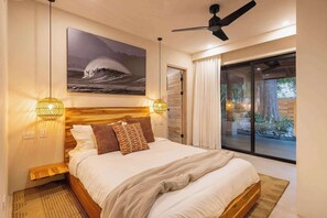 Un dormitorio con cama, ventilador de techo, un cuadro y vistas al exterior.