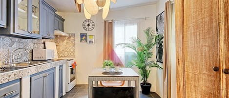 A modern kitchen with grey cabinets, a microwave, and a unique pendant light.