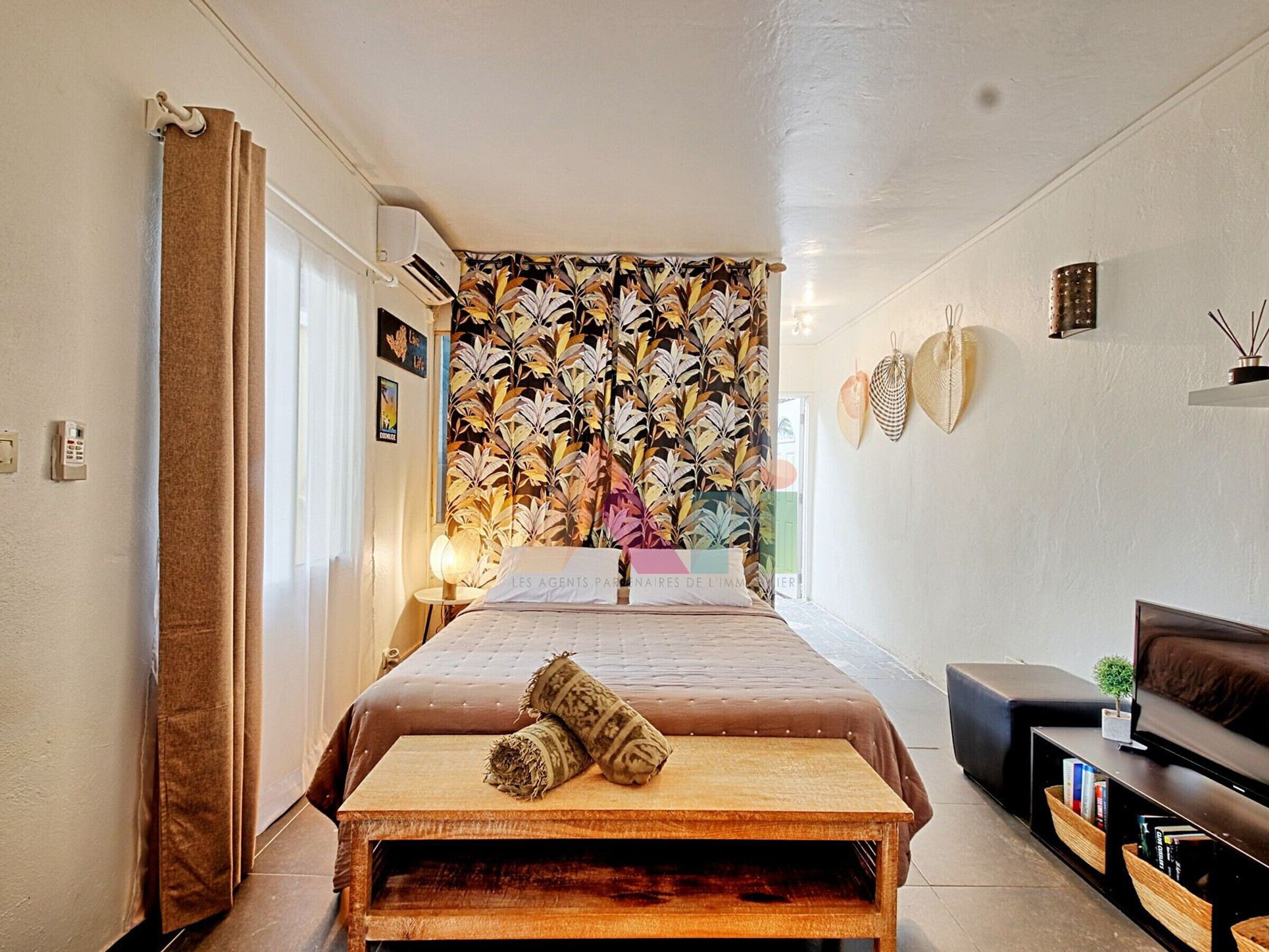 A bedroom with a bed, bedside table, and a TV stand.